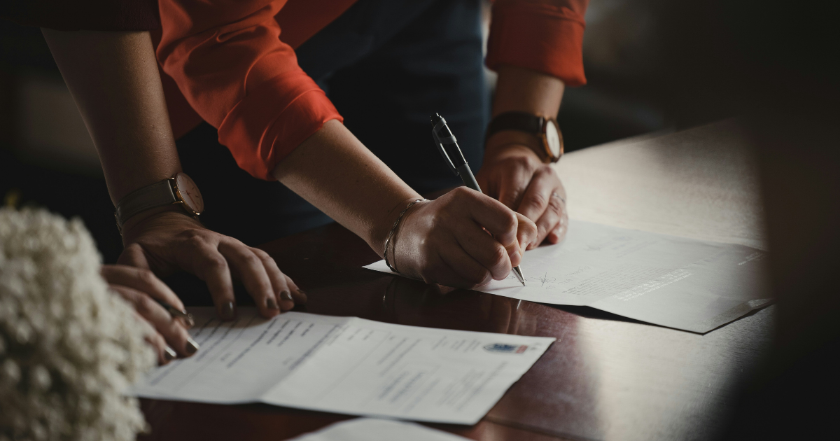 Two sets of hands signing documents